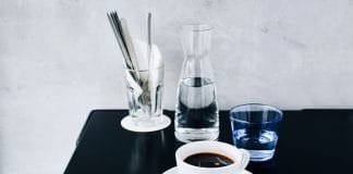 Serwowanie wody i napojów bezalkoholowych – karafki, dzbanki i szklanki, które dodadzą codziennym posiłkom elegancji Minimalistyczna aranżacja stołu z czarną kawą i elegancką szklanką
